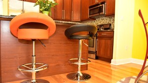 Two bar stools with chrome bases and cushioned seats in a kitchen with wooden cabinets and a granite countertop. - Beach Front,Ideal for family and couples,beautiful place for sunset lovers!!!!!! (Arverne)