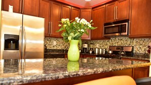 A kitchen with wooden cabinets, a stainless steel refrigerator, a microwave, and a green vase with flowers on the counter. - Beach Front,Ideal for family and couples,beautiful place for sunset lovers!!!!!! (Arverne)