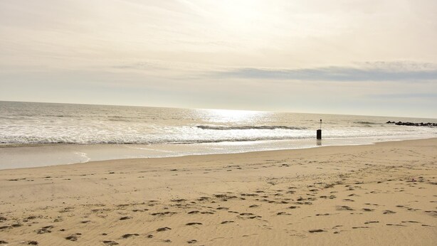 A beach with footprints leading to the water, a pier, and a calm sea under a clear sky. - Beach Front,Ideal for family and couples,beautiful place for sunset lovers!!!!!! (Arverne)