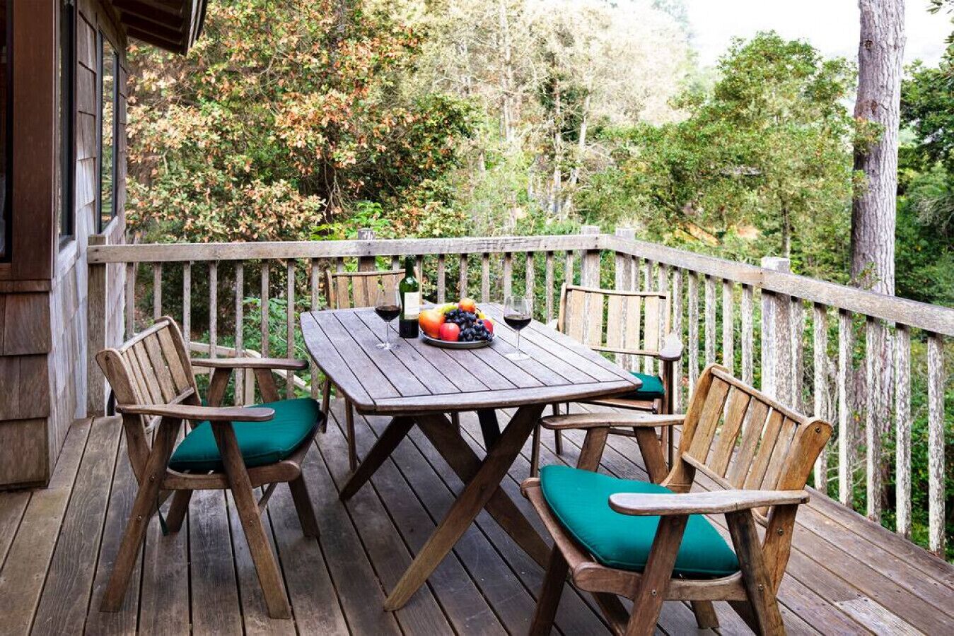 A wooden deck with a table and chairs, surrounded by a wooden railing.