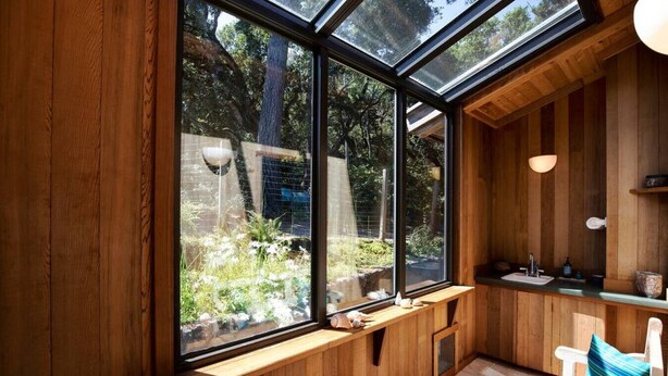 A wooden interior with large windows, a sink, and a bench. - Woodhaven | MCM Inspired Getaway w/ Amazing Views (Inverness)