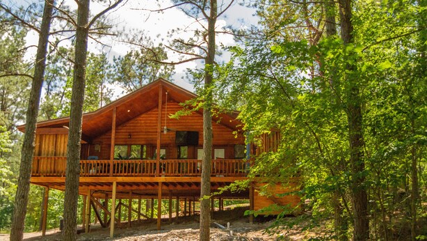 A wooden cabin with a balcony, surrounded by trees. - Beavers Bend State Park entrance 259A , Southern Hill Addition; Wood Knot Cabin (Broken Bow)