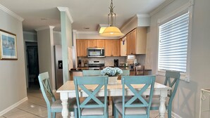 A dining area with a wooden table and chairs, a hanging light fixture, and a window with blinds. - 30 Steps to Sand and Water! Panoramic Sunset and Water Views! Serenity! Pier! (Navarre)