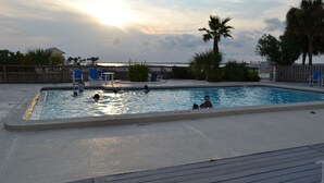 A swimming pool with people, palm trees, and a wooden deck. - 30 Steps to Sand and Water! Panoramic Sunset and Water Views! Serenity! Pier! (Navarre)