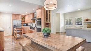 Una cocina amplia con armarios de madera, una isla central y una lámpara colgante.