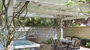 Un patio cubierto con jacuzzi, mobiliario exterior y una parrilla.