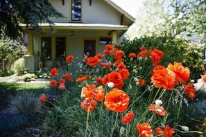 Stroll through the serene garden, surrounded by vibrant flowers and lush greenery, to the classic home with a welcoming porch.