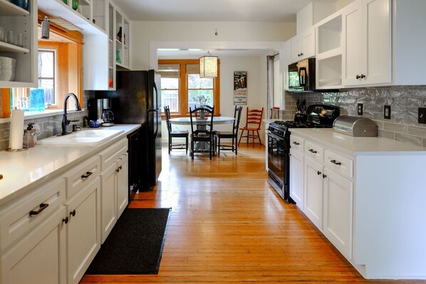 Enjoy cooking in this well-equipped kitchen with a central island, black appliances, and a dining area with a table and chairs.