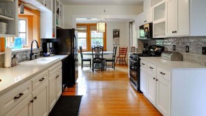 A modern kitchen with white cabinetry, a central island, and a dining area with chairs.