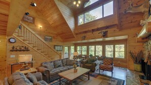 Eine geräumige Holzhütte mit großem Wohnbereich, einer Treppe und einem Kamin.