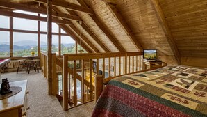 A cozy attic bedroom with a large bed, a desk, and a television. - Secluded with Mountain View,Wifi Gameroom and Hot tub Close to Pigeon Forge (Sevierville)