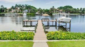 A marina with docked boats, a wooden walkway leading to the water, and lush greenery surrounding the area.