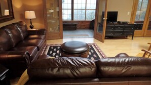 Un salón con un sofá de cuero marrón, una mesa de centro de madera y un televisor sobre un mueble.