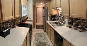 A kitchen with wooden cabinets, a microwave, a stove, a sink, and a dishwasher. - Great condo in mountain village. Close to Yellowstone  (Big sky)