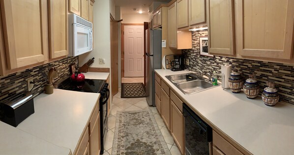 A kitchen with wooden cabinets, a microwave, a stove, a sink, and a dishwasher.