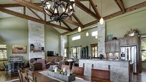 A spacious kitchen with a central island, wooden beams, and a large chandelier. - DREAM HOME w/ Amazing View! Movie Theater, Pool, Hot Tub, Game Room (San Marcos)
