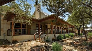 A two-story house with a covered porch, stone pathway, and a small garden area. - DREAM HOME w/ Amazing View! Movie Theater, Pool, Hot Tub, Game Room (San Marcos)