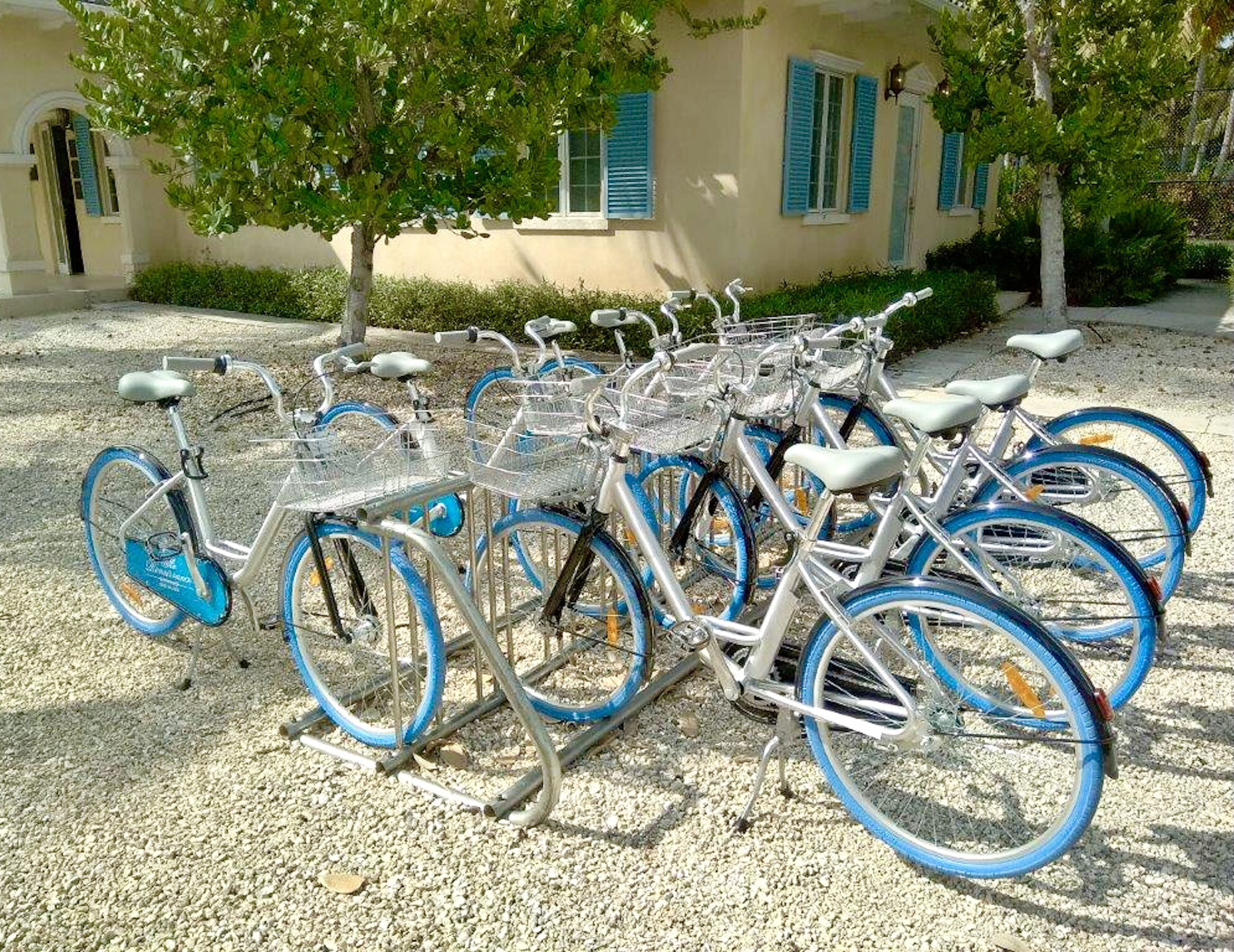 Varias bicicletas estacionadas frente a un edificio con contraventanas azules.
