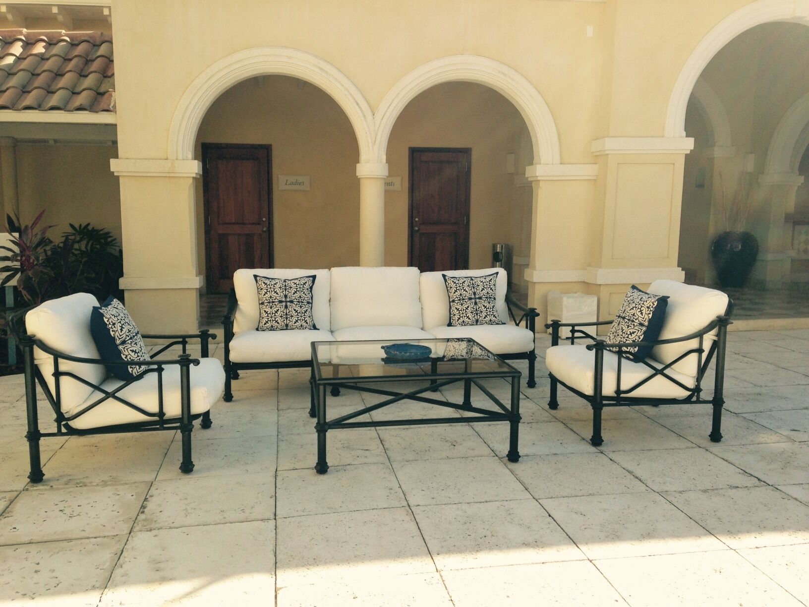 A seating area with a white sofa and armchairs, a coffee table, and a tiled floor.