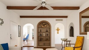 A living room with a sofa, a wooden coffee table with a remote control, a yellow armchair, and a bookshelf. - Stay close to concerts, sports and culture in our artistic historic monarch home (Phoenix)