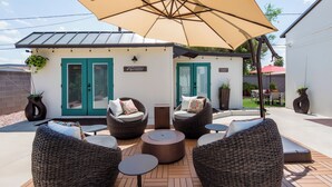 An outdoor patio with wicker furniture, a large umbrella, and a sign that reads "welcome to garden." - Stay close to concerts, sports and culture in our artistic historic monarch home (Phoenix)