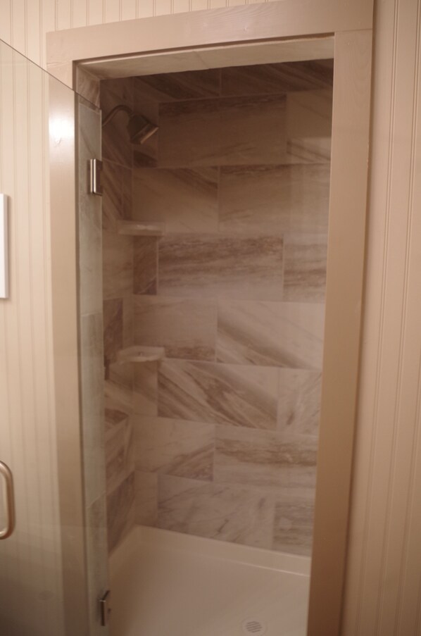 A shower with a glass door and marble tiles. - Beautiful historic 3 bed 3 bath Guest House w old stone wine cellar!! (Hermann)