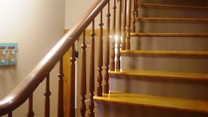 A wooden staircase with a curved handrail and a light fixture above.