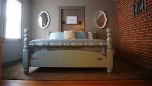 A bedroom with a wooden bed, a brick wall, and a window.