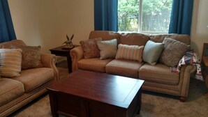 Una sala de estar con un sofá de cuero marrón, una mesa de centro de madera y una mesita auxiliar con un adorno.