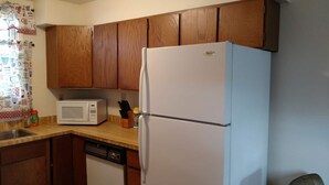 Una cocina con armarios de madera, un refrigerador blanco, un microondas y un lavavajillas.