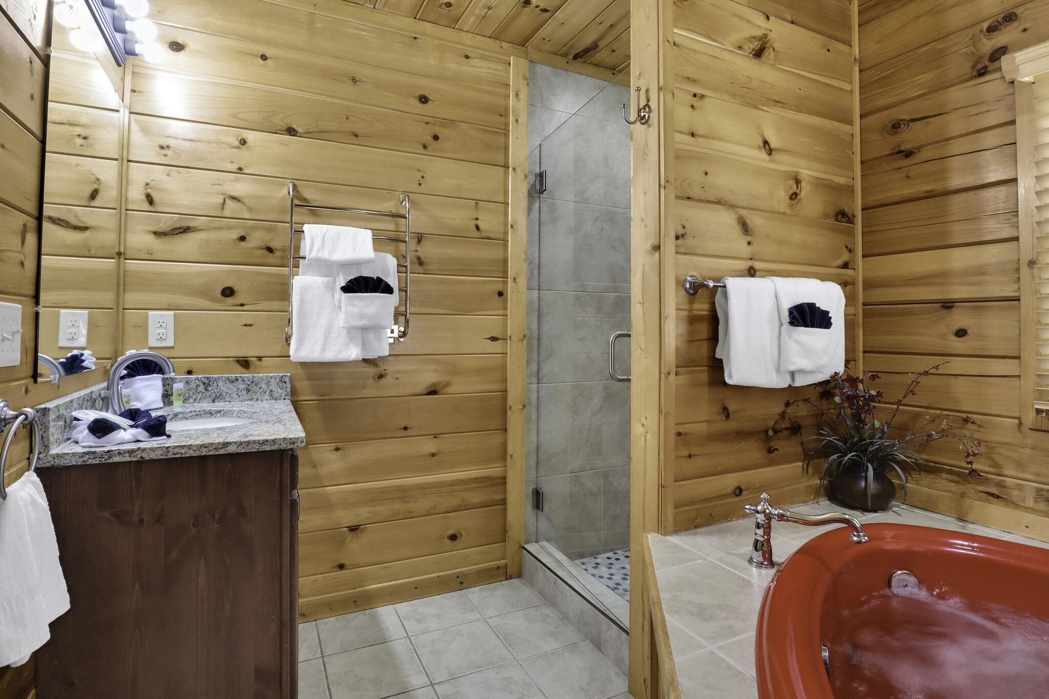 Un baño revestido de paneles de madera, con ducha, lavabo y bañera.