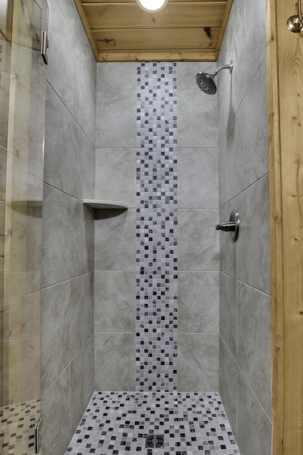 A shower with a tiled wall and a wooden ceiling.