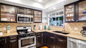 A modern kitchen with dark wood cabinets, stainless steel appliances, and a window with a view. - Beautiful Ocean View (San Clemente)