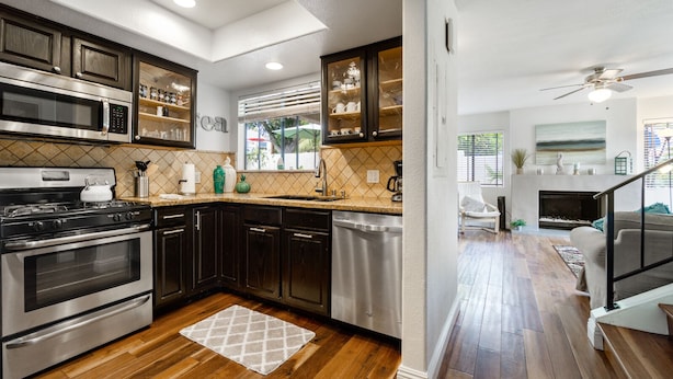 A modern kitchen with dark cabinetry, stainless steel appliances, and a wooden floor. - Beautiful Ocean View (San Clemente)