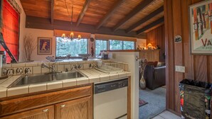 A kitchen with wooden cabinets, a dishwasher, and a large window.