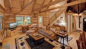 A log cabin interior with a wooden ceiling, a fireplace, a television, a sofa set, and a staircase. - Arroyito-Mtn Cabin, Pet-Friendly, Wood Fireplace, Shared Firepit, Charcoal Grill (Seven Devils)