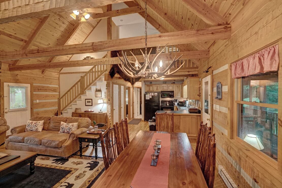 Ein Holzblockhaus-Interieur mit Essbereich, Küche und Treppe.