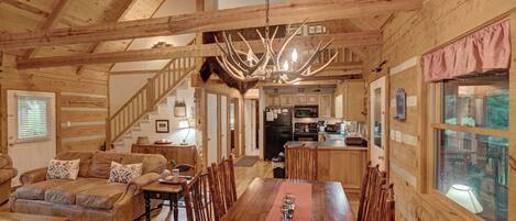 Ein Holzblockhaus-Interieur mit Essbereich, Küche und Treppe.
