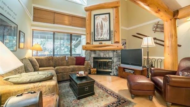 A cozy living room with a stone fireplace, a sofa, a coffee table, and a television.