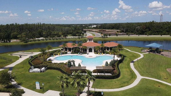 A resort with a large central pool, palm trees, and a lake. - SUNCITY CENTER HOUSE WITH GORGEOUS LAKE VIEW. (Wimauma)