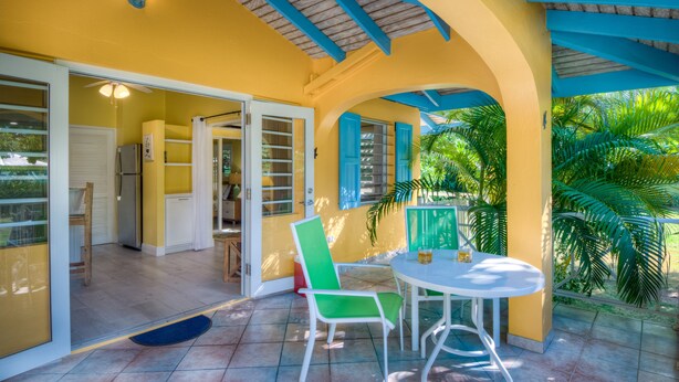 A covered patio area with a table and chairs, a ceiling fan, and a view of the outdoors. - Cane Garden Bay Cottage #4 (Tortola)