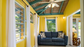 A room with a blue sofa, a ceiling fan, and a window with curtains. - Cane Garden Bay Cottage #4 (Tortola)