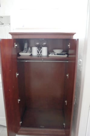 Features a spacious wardrobe with a mirrored interior and a shelf for storage.