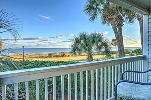 Enjoy the ocean view from this balcony with a single chair and a comfortable cushion.
