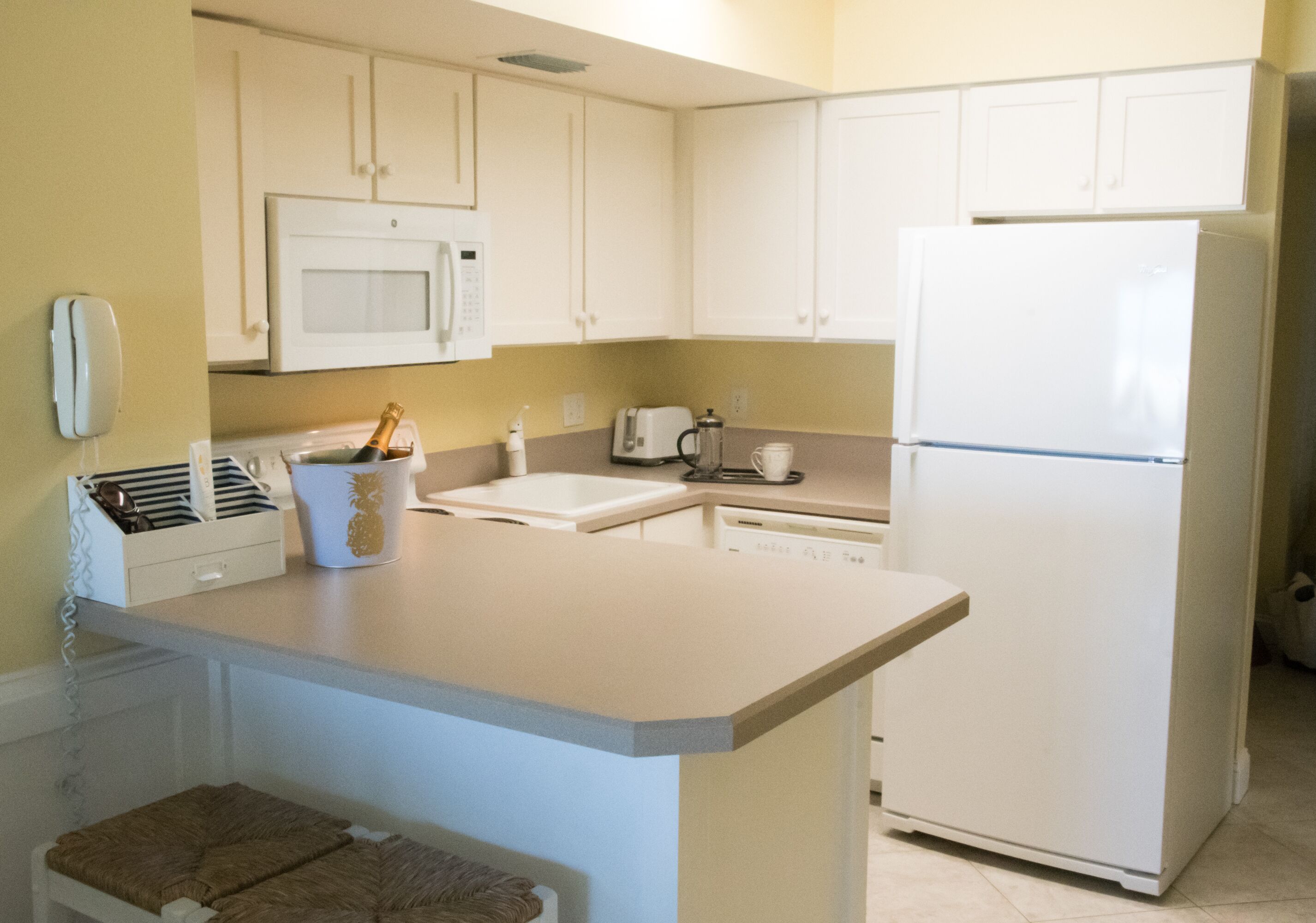 A kitchen with white cabinets, a microwave, a refrigerator, a coffee maker, and a toaster.