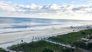 A beach with a clear sky, a sandy shore, and a few people in the distance.