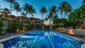 A swimming pool with clear blue water, surrounded by palm trees and a building with balconies. -  Salt Water Pool⛱️  Ocean View 🌊 Hualalai View🌋 140+ 5 Star Reviews 🌟🌟🌟🌟🌟 (Waikoloa Village)