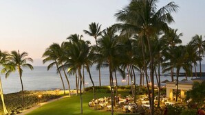 A resort with outdoor dining areas, palm trees, and a view of the ocean. -  Salt Water Pool⛱️  Ocean View 🌊 Hualalai View🌋 140+ 5 Star Reviews 🌟🌟🌟🌟🌟 (Waikoloa Village)