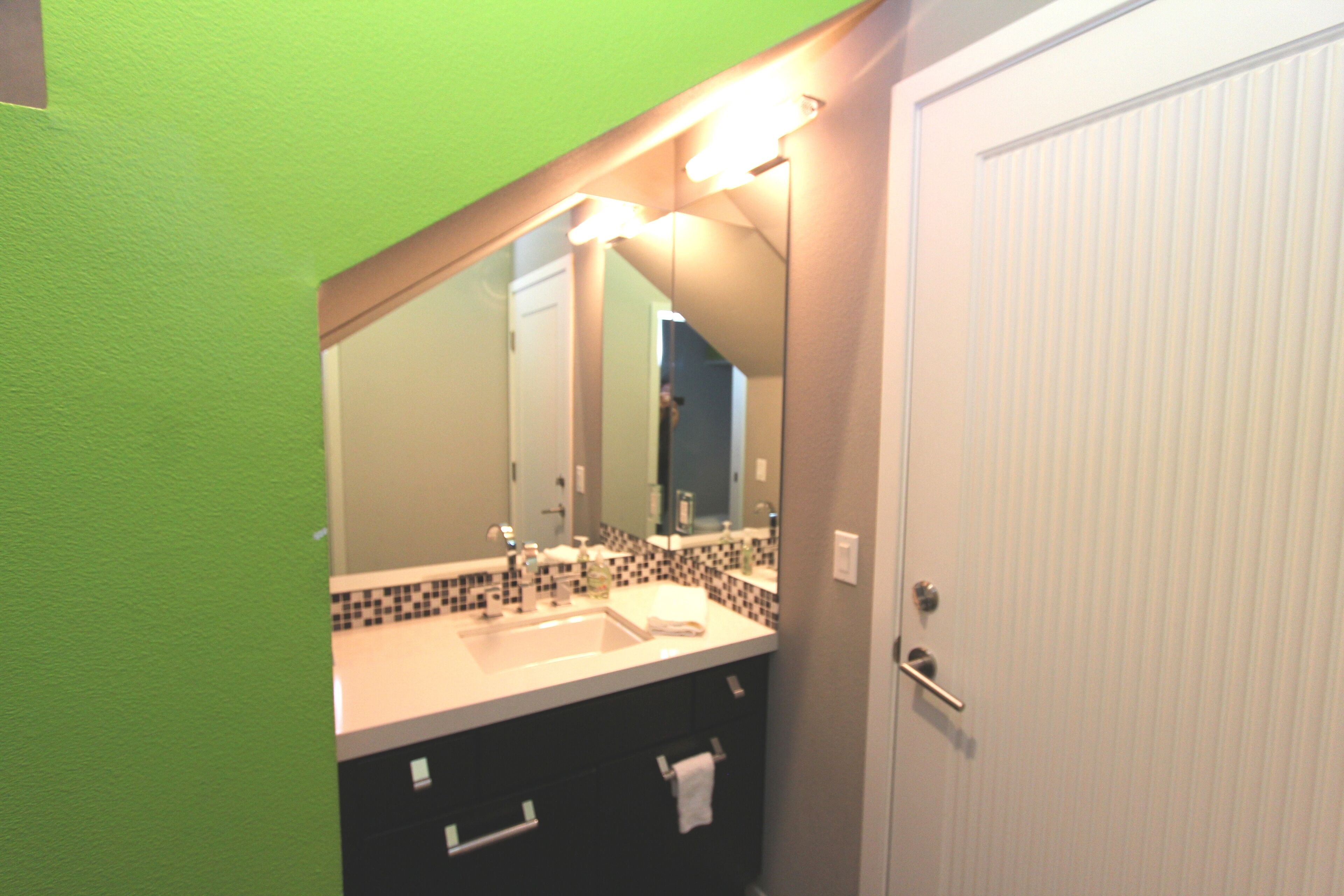 A bathroom with a sink, mirror, and towel rack.