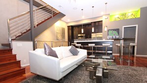 Ein modernes Wohnzimmer mit einem weißen Sofa, einem Glastisch und einer Treppe, die zu einer oberen Ebene führt.